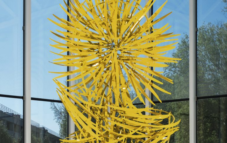 Close up view of an abstract yellow statue in the middle of an indoor fountain.